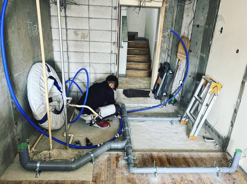 作業風景：床下の給排水管を施工する職人